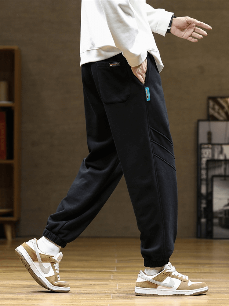 Sporty baggy casual joggers pants for men with side pockets, featuring flat-front style and drawstring closure, in a modern setting.